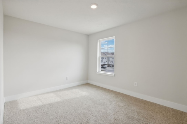 spare room with light carpet and baseboards