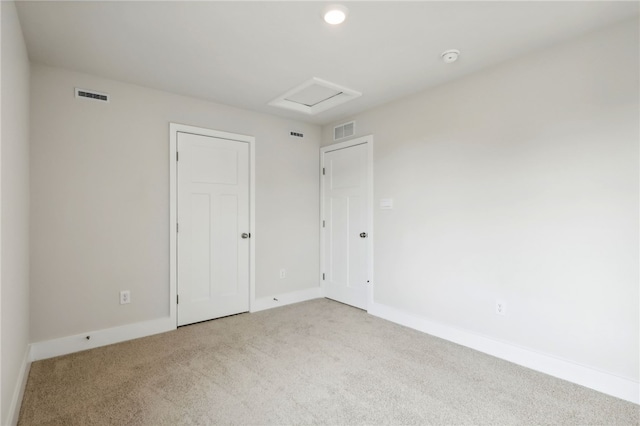 empty room featuring carpet floors, attic access, visible vents, and baseboards