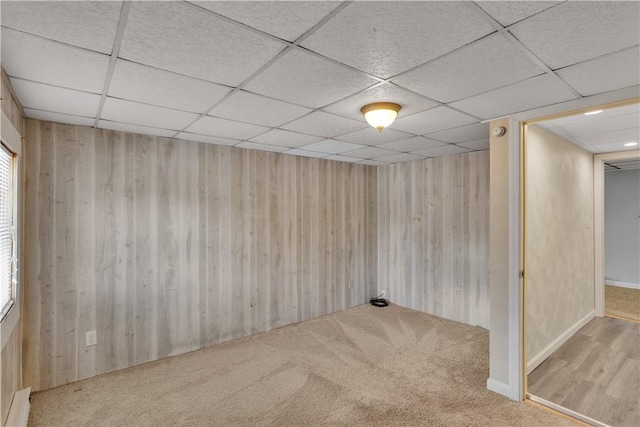 interior space featuring carpet, a drop ceiling, and wooden walls