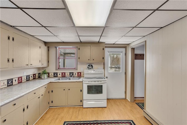 kitchen with a sink, light countertops, cream cabinetry, light wood-type flooring, and white electric range oven