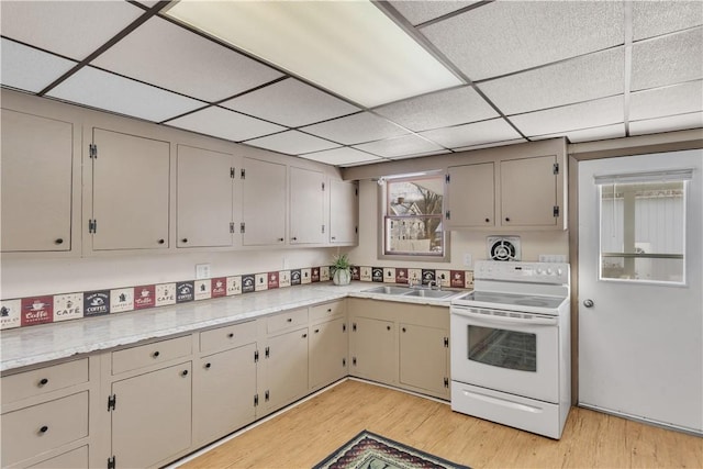 kitchen with light wood-type flooring, light countertops, a sink, and white electric range oven