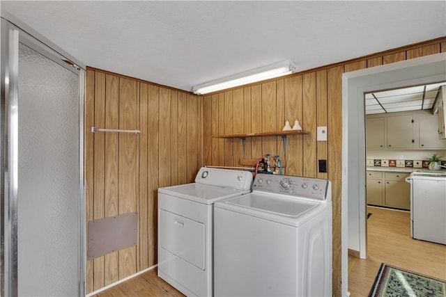 washroom featuring wooden walls, light wood finished floors, and washing machine and clothes dryer