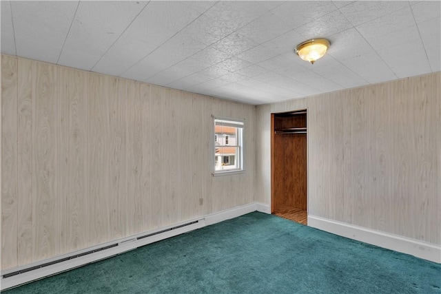 unfurnished room with a baseboard heating unit, carpet floors, and baseboards