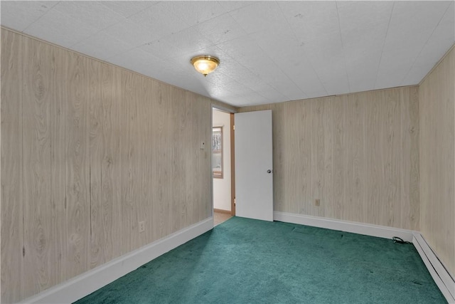 carpeted spare room featuring baseboards, baseboard heating, and wooden walls