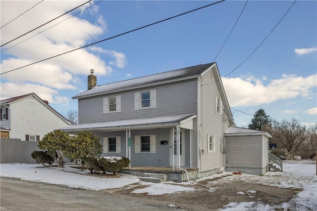 view of front of property with covered porch, a chimney, and fence