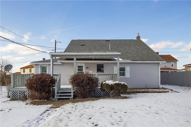 snow covered house with a porch, fence, and a chimney