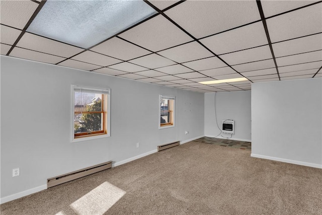 basement featuring carpet, heating unit, a baseboard radiator, a baseboard heating unit, and a drop ceiling