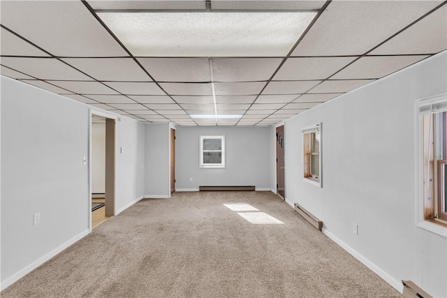 empty room with a paneled ceiling, a baseboard radiator, baseboard heating, and carpet flooring