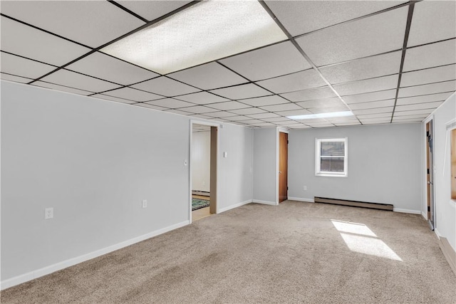 interior space with a drop ceiling, baseboard heating, carpet, and baseboards