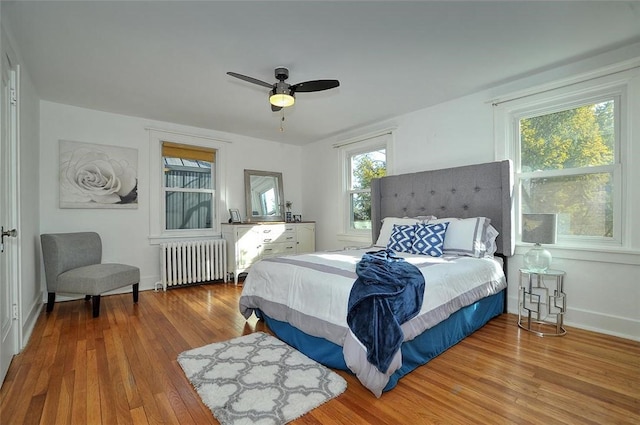 bedroom featuring radiator, a ceiling fan, baseboards, and wood finished floors