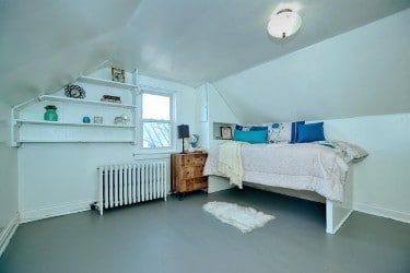 bedroom with radiator, finished concrete flooring, baseboards, and vaulted ceiling