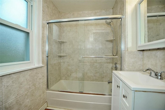 full bathroom with combined bath / shower with glass door, tile walls, and vanity