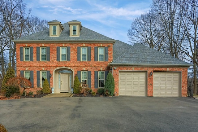 view of front facade with aphalt driveway, an attached garage, brick siding, and a shingled roof