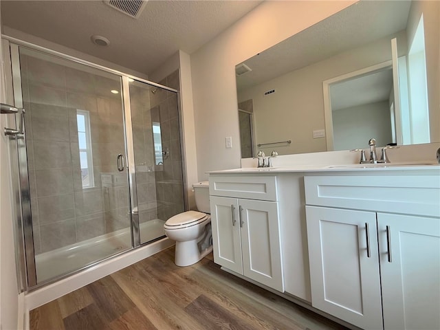 full bathroom featuring visible vents, toilet, a sink, a shower stall, and wood finished floors