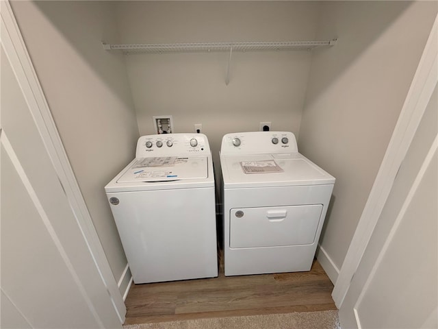 clothes washing area featuring washing machine and clothes dryer and wood finished floors