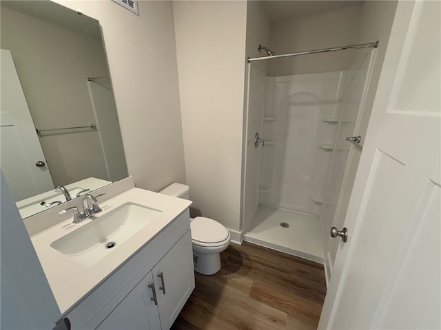 bathroom featuring a shower, vanity, wood finished floors, and toilet