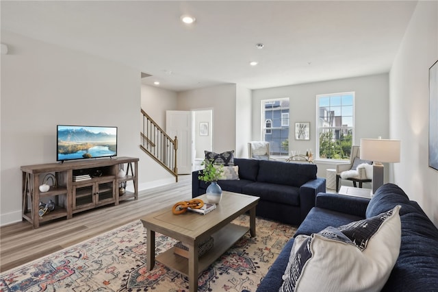 living area with baseboards, stairway, recessed lighting, and light wood-style floors