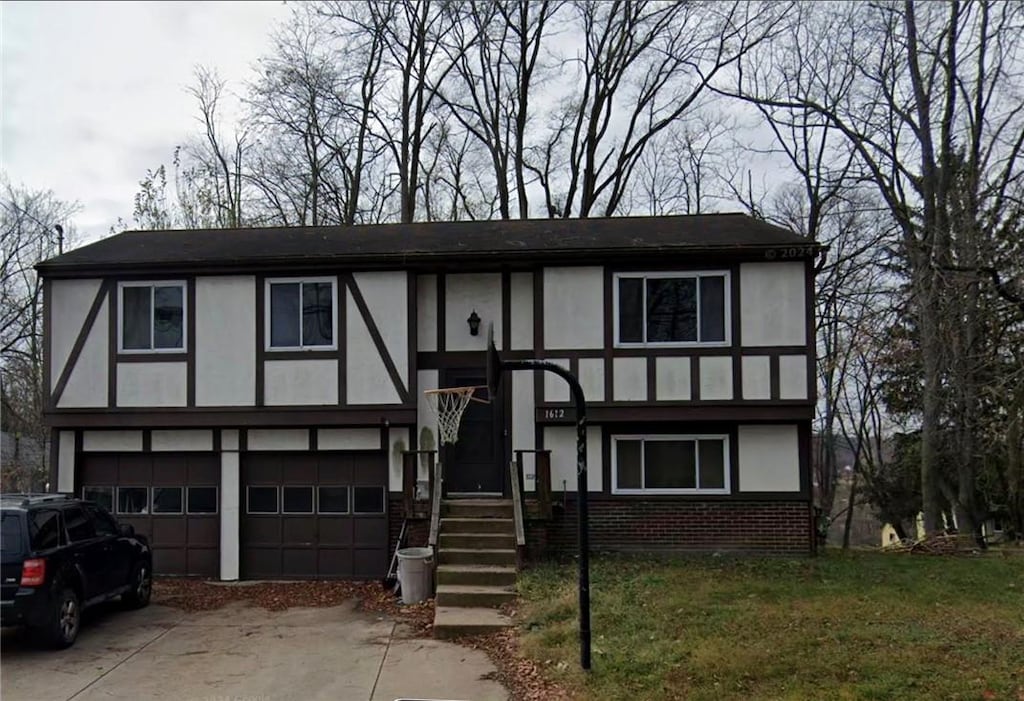 tudor house featuring a garage, brick siding, driveway, and stucco siding