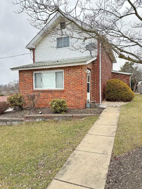 view of property exterior with a lawn and brick siding