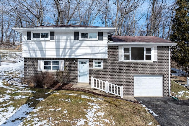 split level home featuring brick siding, an attached garage, and aphalt driveway