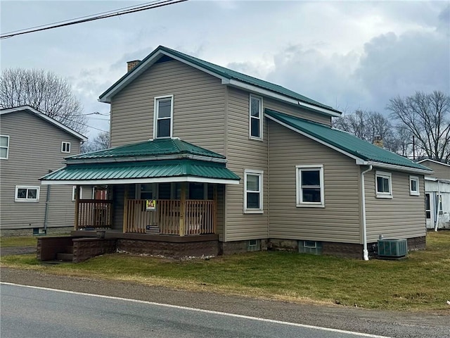 view of front facade featuring a chimney, a porch, metal roof, central air condition unit, and a front lawn