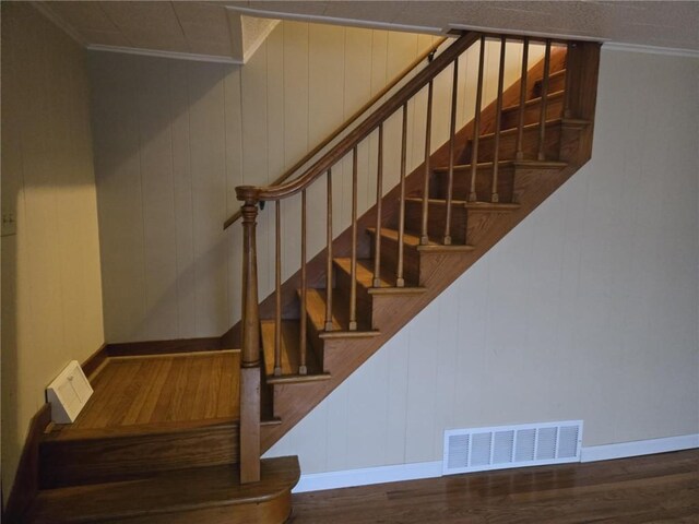 stairway featuring wood finished floors, visible vents, and crown molding