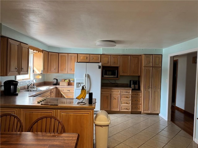 kitchen with white refrigerator with ice dispenser, black electric stovetop, light tile patterned floors, stainless steel microwave, and a sink