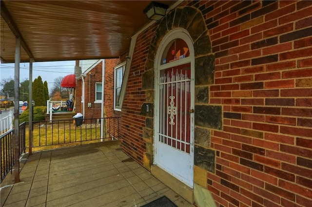 view of exterior entry featuring brick siding and a porch