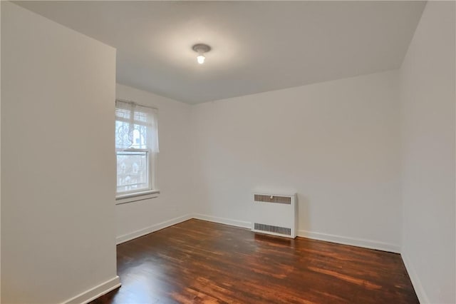 spare room with radiator heating unit, baseboards, and wood finished floors