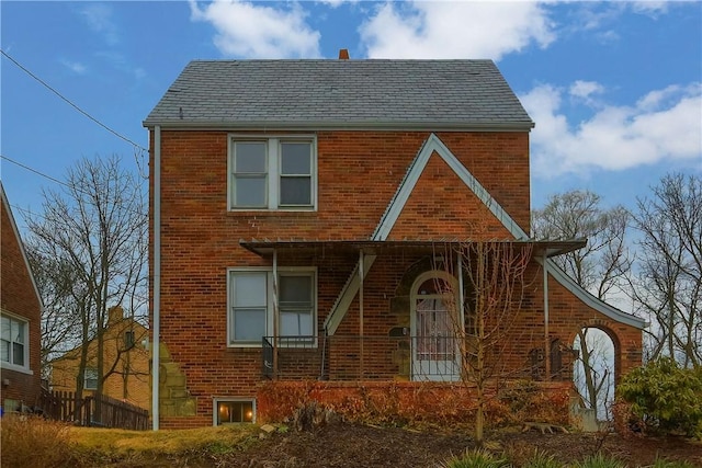 tudor-style house with a porch and brick siding