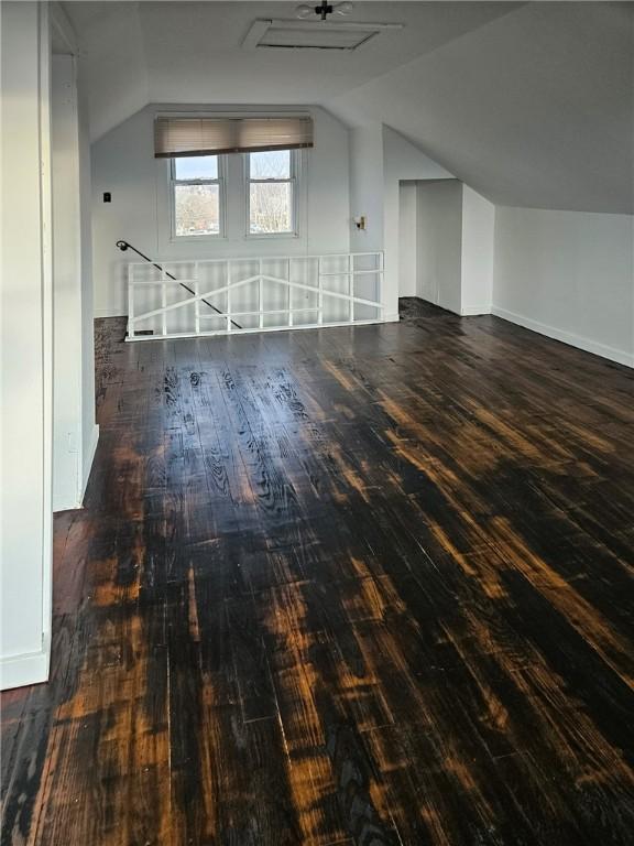 additional living space with wood-type flooring, vaulted ceiling, and baseboards