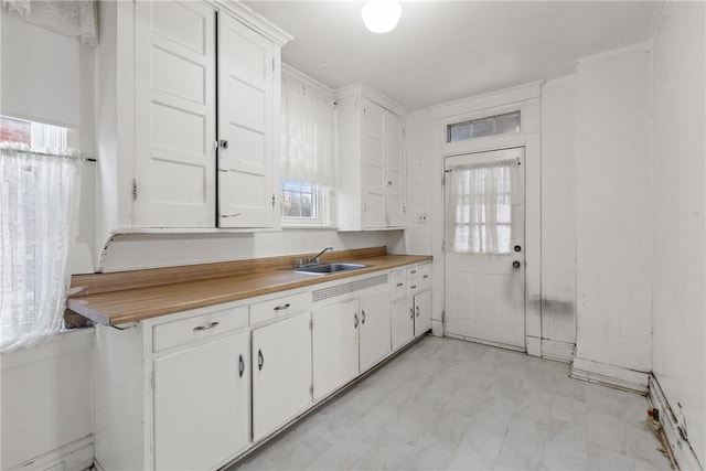 kitchen featuring light floors, white cabinetry, light countertops, and a sink