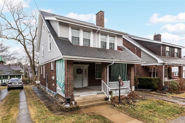 view of front of house with a porch, a chimney, and brick siding