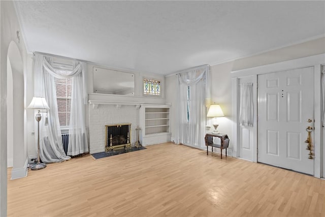 living room featuring a fireplace, wood finished floors, and crown molding