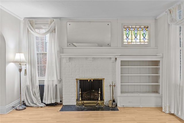 living area with a wealth of natural light, a brick fireplace, and wood finished floors