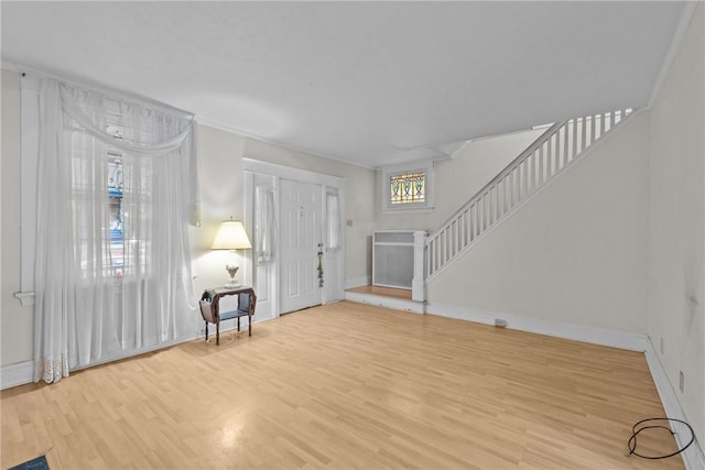 foyer with baseboards, stairway, wood finished floors, and ornamental molding