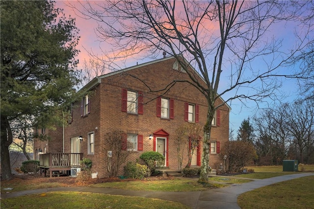 view of front of home with brick siding and a lawn