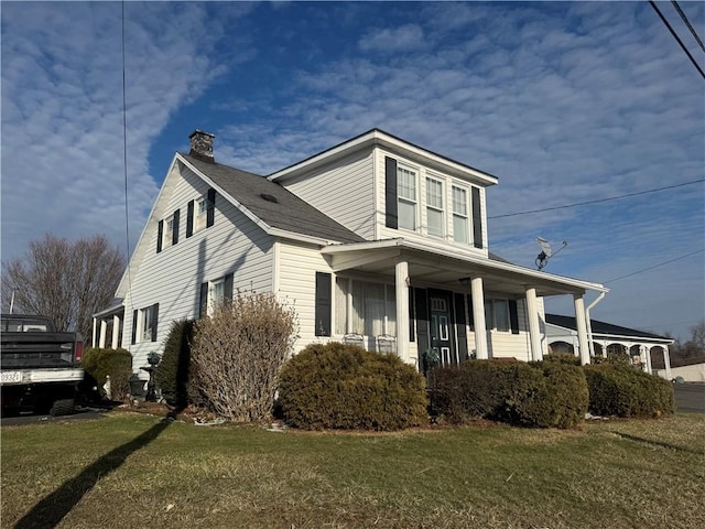 view of side of property with a yard and a chimney