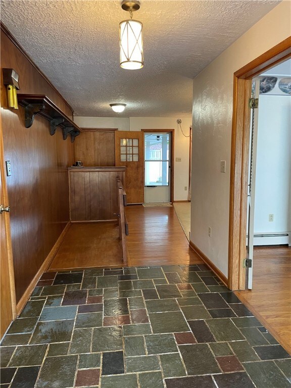 3503 State Route 208, Wilmington Twp, PA 16142 - corridor with a baseboard heating unit, a textured ceiling, wood walls, and stone finish floors