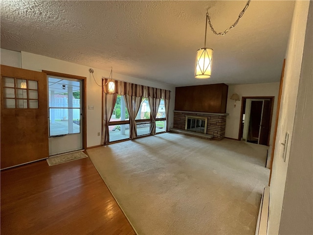 3503 State Route 208, Wilmington Twp, PA 16142 - unfurnished living room with a baseboard heating unit, a fireplace, a textured ceiling, and wood finished floors