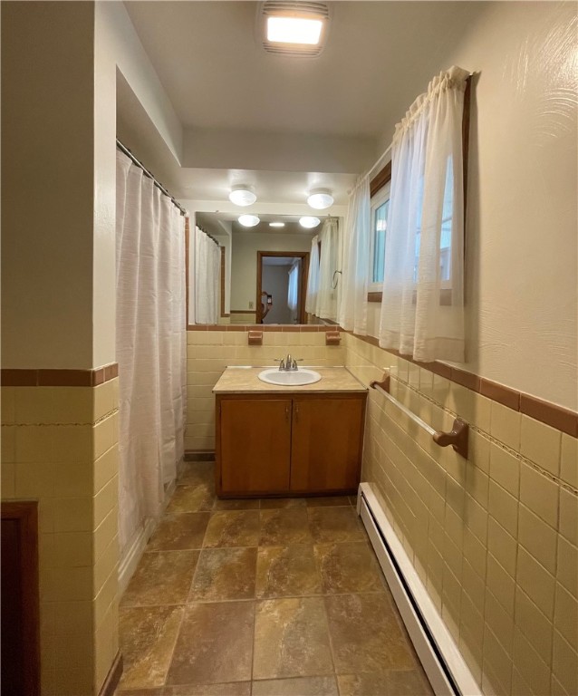 3503 State Route 208, Wilmington Twp, PA 16142 - bathroom featuring tile walls, a baseboard radiator, vanity, stone finish flooring, and wainscoting