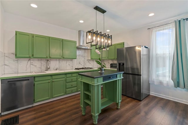 kitchen with visible vents, stainless steel appliances, wall chimney range hood, green cabinets, and a sink