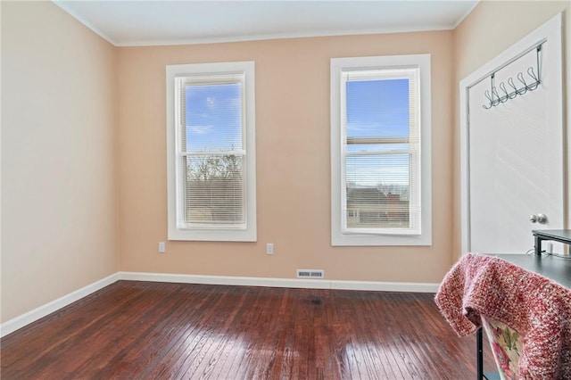 unfurnished room featuring dark wood-style floors, ornamental molding, visible vents, and baseboards