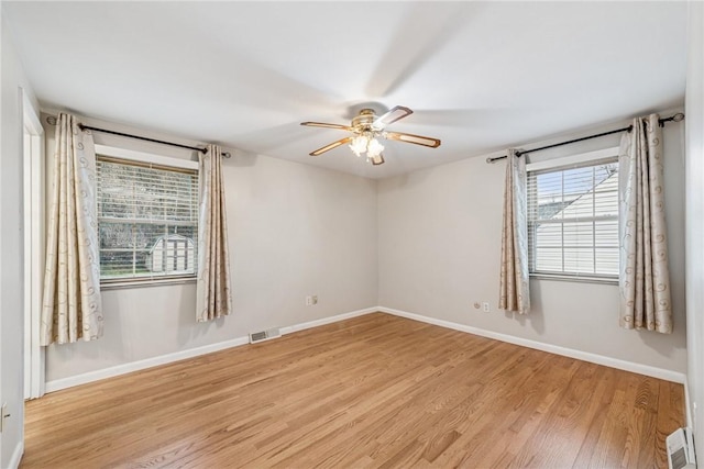 spare room with a healthy amount of sunlight, baseboards, visible vents, and wood finished floors