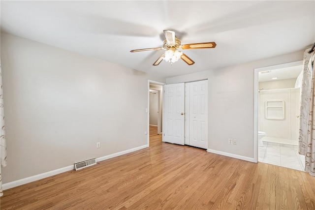 unfurnished bedroom featuring a closet, visible vents, ensuite bath, light wood-type flooring, and baseboards