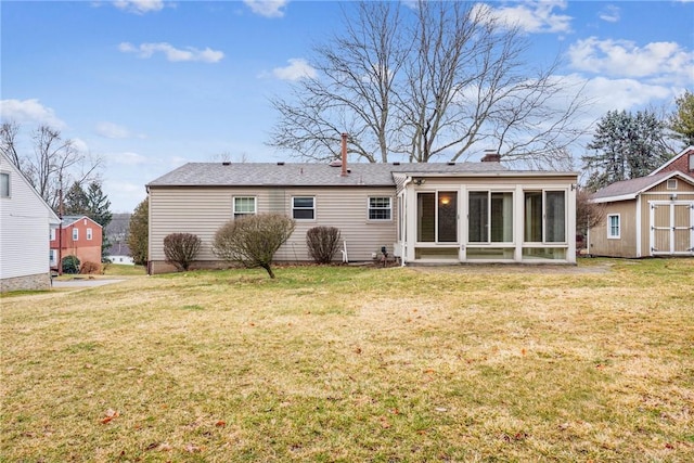 rear view of property featuring a sunroom, a chimney, a yard, an outdoor structure, and a shed