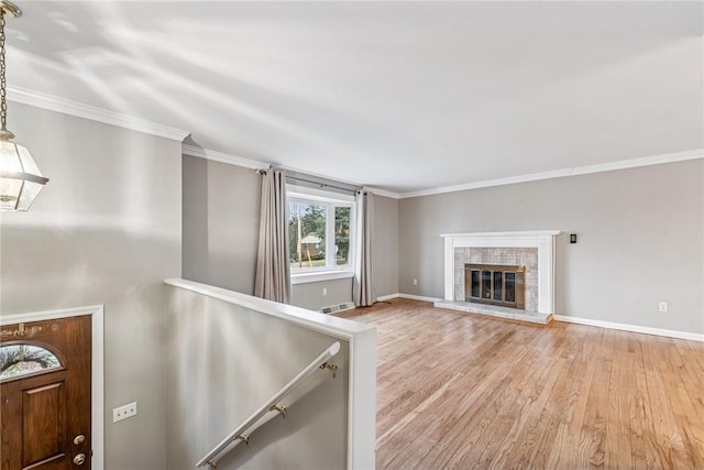 unfurnished living room with light wood-style flooring, a glass covered fireplace, visible vents, and crown molding