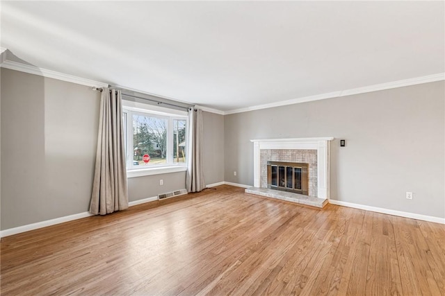 unfurnished living room featuring baseboards, a brick fireplace, visible vents, and light wood-style floors