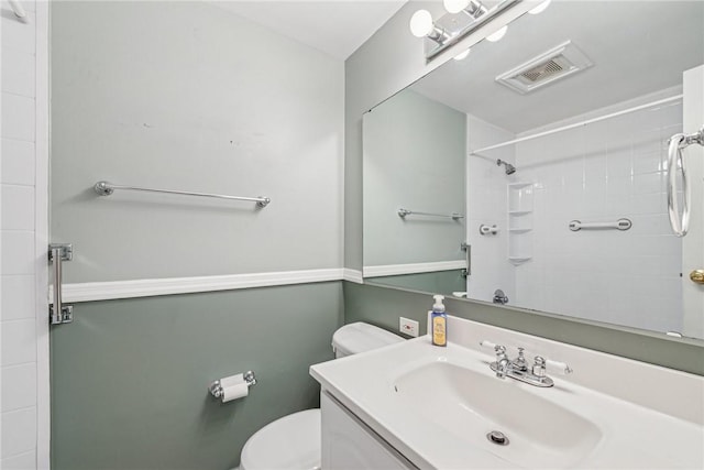 bathroom with toilet, tiled shower, vanity, and visible vents