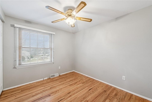 spare room featuring a ceiling fan, visible vents, baseboards, and wood finished floors